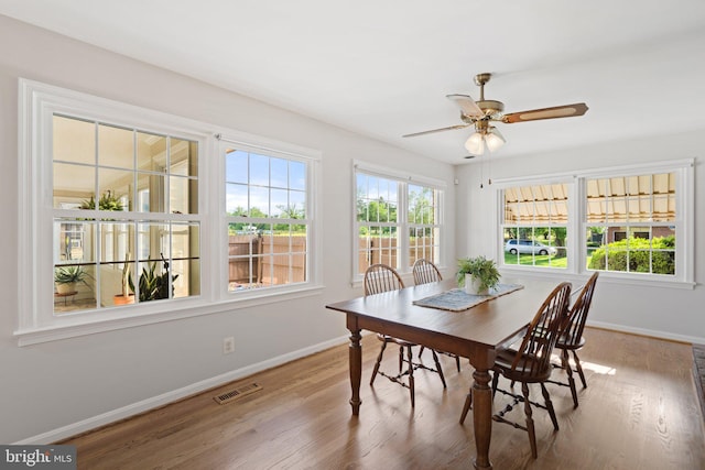 dining area featuring a ceiling fan, visible vents, baseboards, and wood finished floors