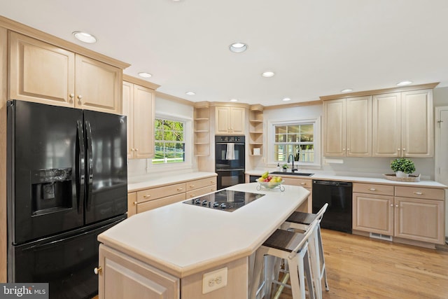 kitchen featuring open shelves, light countertops, light brown cabinetry, a sink, and black appliances