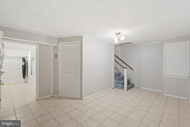 finished basement featuring light tile patterned floors, baseboards, and stairway