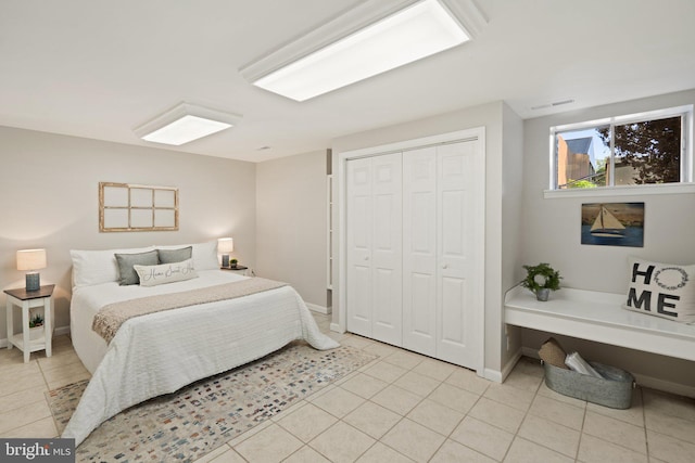 bedroom featuring a closet, light tile patterned flooring, visible vents, and baseboards