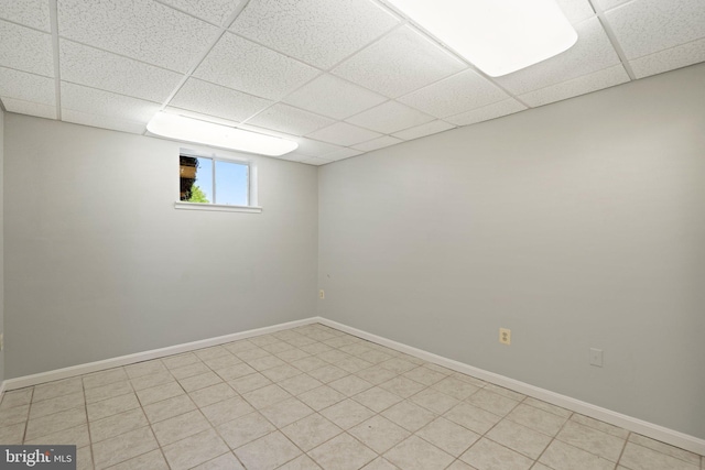 basement featuring a paneled ceiling and baseboards