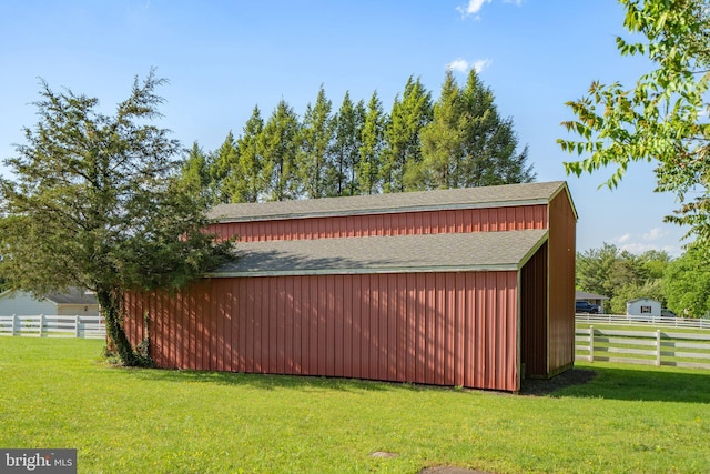 exterior space with a shingled roof, a lawn, an outdoor structure, and fence