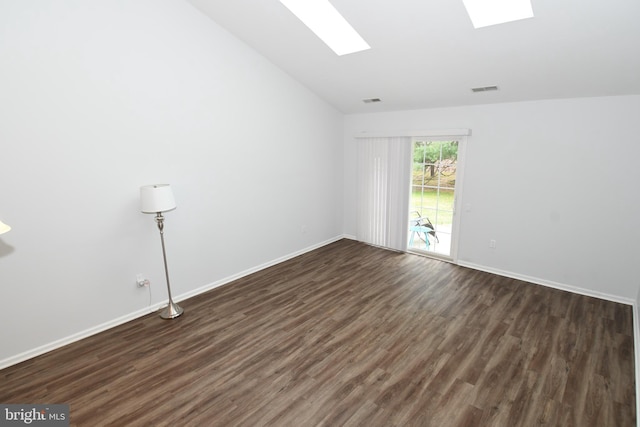 empty room featuring vaulted ceiling with skylight, dark wood-style floors, visible vents, and baseboards