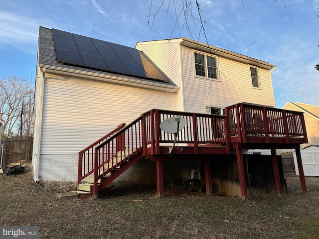 rear view of property with a deck and solar panels