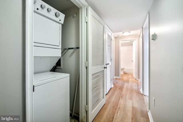 washroom with stacked washer / drying machine and light wood-type flooring