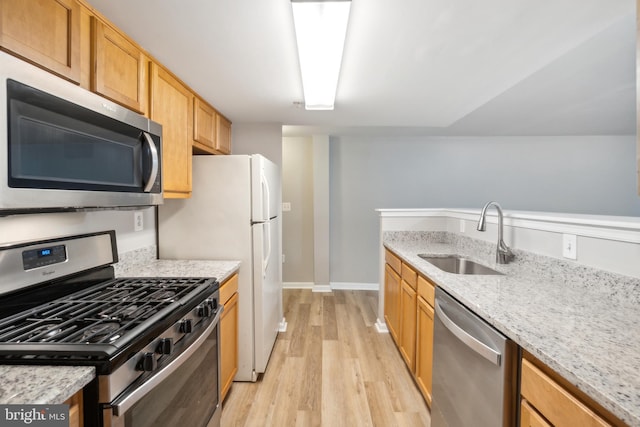 kitchen featuring sink, stainless steel appliances, light hardwood / wood-style floors, and light stone countertops