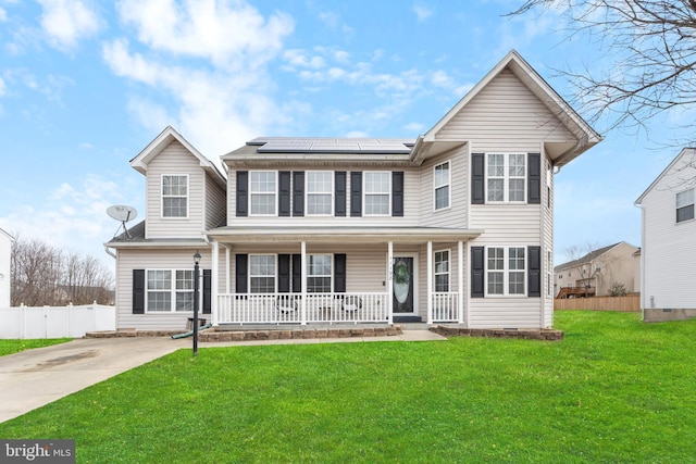 view of front of home with roof mounted solar panels, fence, a porch, and a front yard