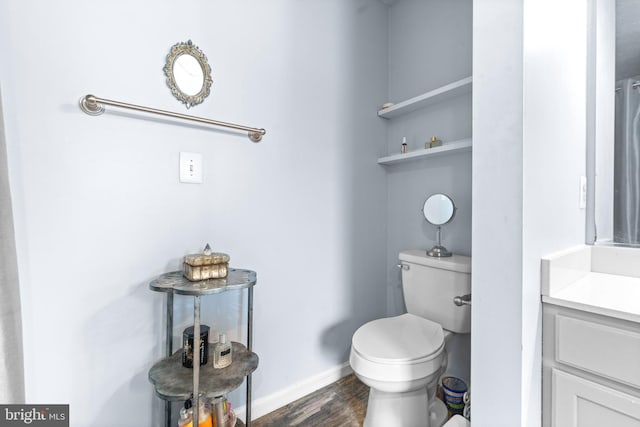 bathroom with baseboards, vanity, toilet, and wood finished floors