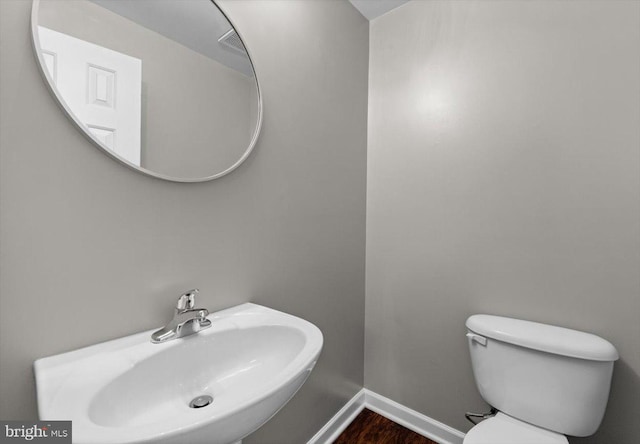 bathroom with hardwood / wood-style flooring, sink, and toilet