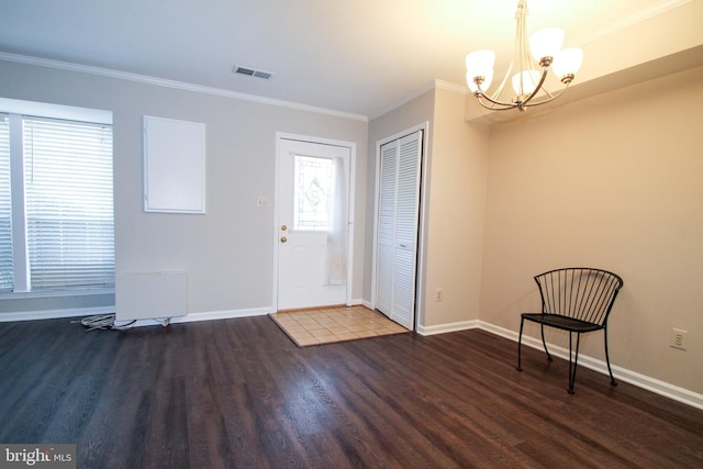 foyer featuring an inviting chandelier, dark wood-type flooring, and ornamental molding