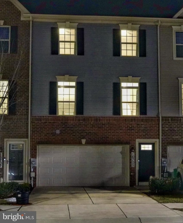 multi unit property featuring a garage, driveway, and brick siding