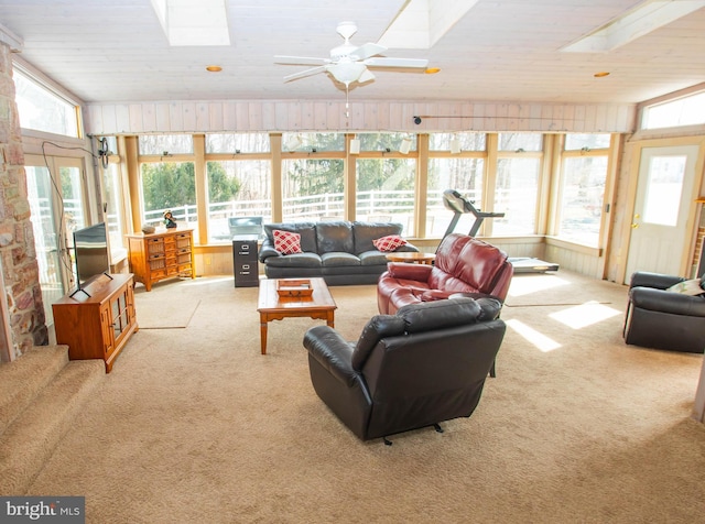 living room featuring vaulted ceiling with skylight, carpet, ceiling fan, and a wealth of natural light