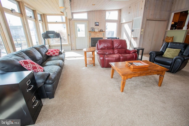 living room featuring wood walls, wood ceiling, a brick fireplace, and carpet flooring