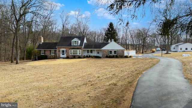 view of front of property featuring driveway, a front lawn, and a chimney