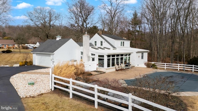 back of property featuring a garage, aphalt driveway, a chimney, and fence