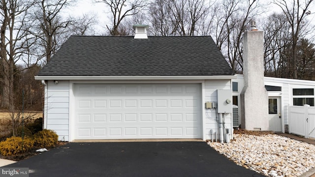 view of front facade with roof with shingles, crawl space, a chimney, and a detached garage