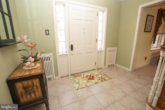 entryway with light tile patterned floors, radiator heating unit, and baseboards