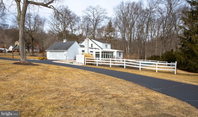 view of front of house featuring an attached garage, a fenced front yard, a chimney, and a front yard