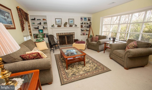 carpeted living area with a glass covered fireplace, visible vents, and built in features