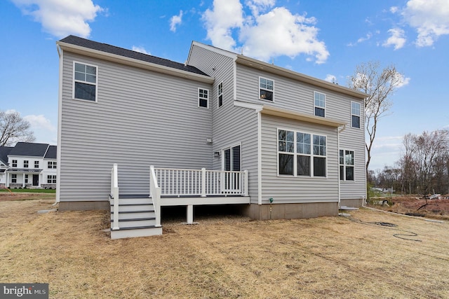 rear view of house featuring a deck and a lawn