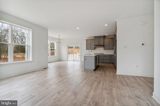 kitchen featuring sink, an inviting chandelier, decorative light fixtures, a kitchen island, and light hardwood / wood-style floors