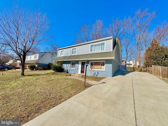 view of front of property featuring brick siding, a front lawn, fence, concrete driveway, and roof with shingles