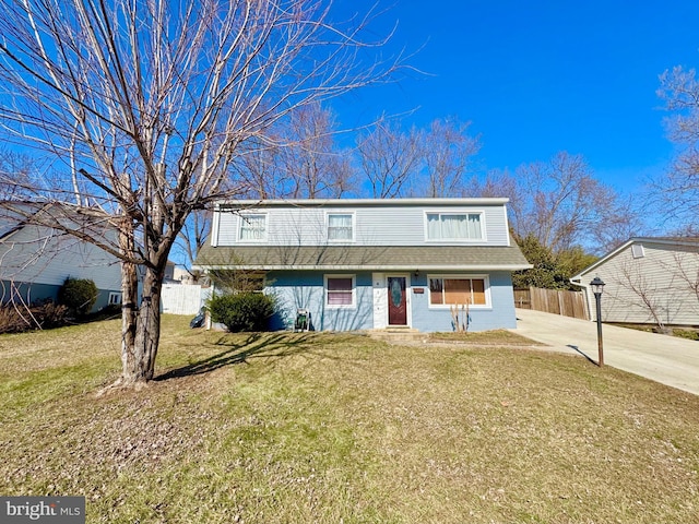 view of front of house with a front lawn, fence, roof with shingles, concrete driveway, and brick siding