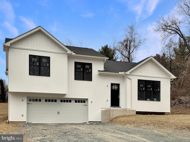 modern inspired farmhouse with gravel driveway, a garage, and roof with shingles