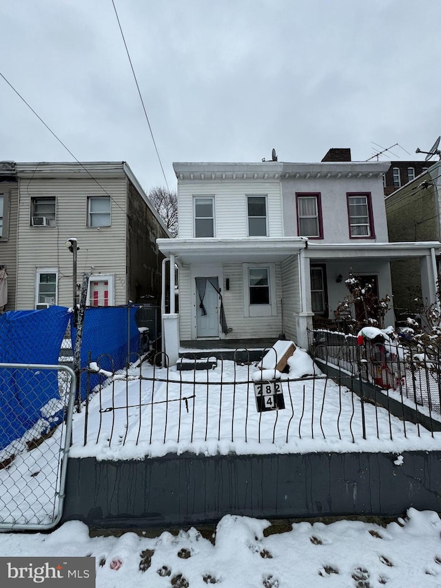 snow covered rear of property with covered porch