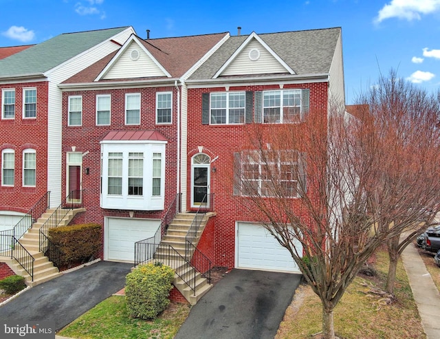 townhome / multi-family property with aphalt driveway, a garage, brick siding, and a shingled roof