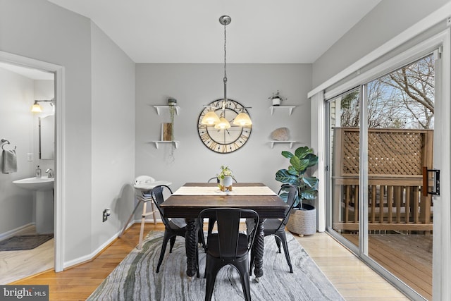 dining room with light wood-style floors, baseboards, and a chandelier