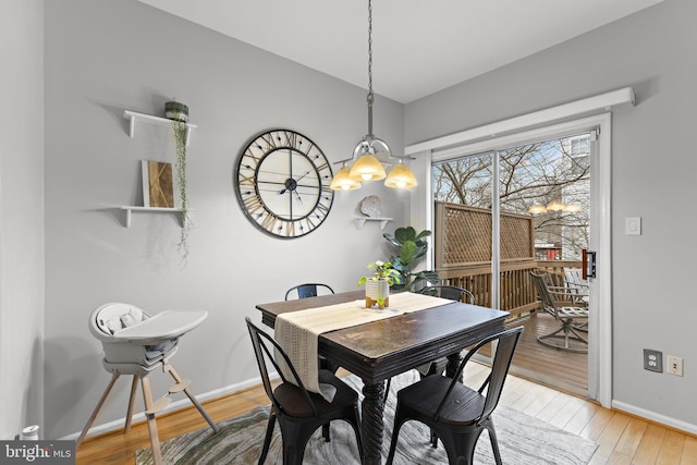 dining room featuring baseboards, lofted ceiling, and light wood-style flooring