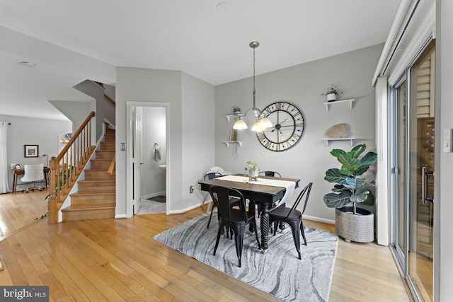 dining space with light wood-type flooring, baseboards, a chandelier, and stairs