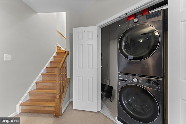 laundry room featuring laundry area, stacked washer / dryer, carpet flooring, and baseboards