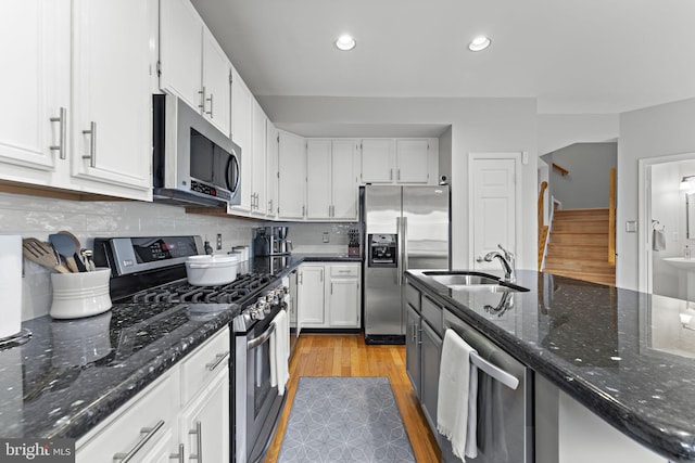 kitchen with a sink, white cabinets, tasteful backsplash, and stainless steel appliances