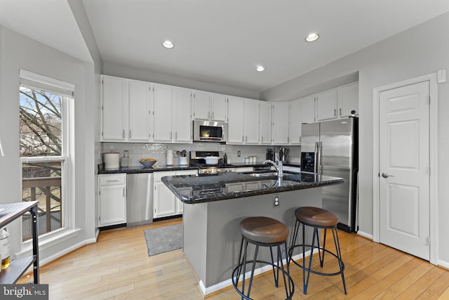 kitchen featuring dark stone countertops, white cabinets, appliances with stainless steel finishes, and a sink