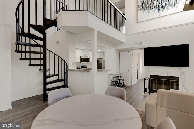 dining area with stairs, visible vents, a premium fireplace, and wood finished floors