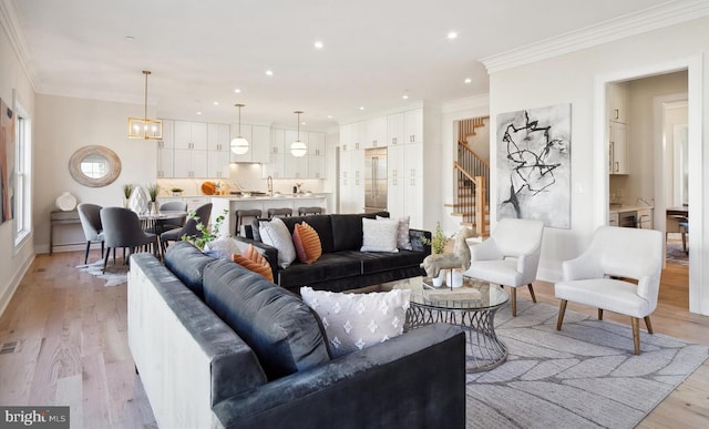 living room featuring a notable chandelier, ornamental molding, and light wood-type flooring