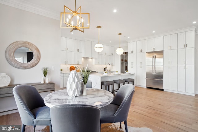 dining room with ornamental molding, a chandelier, and light hardwood / wood-style floors