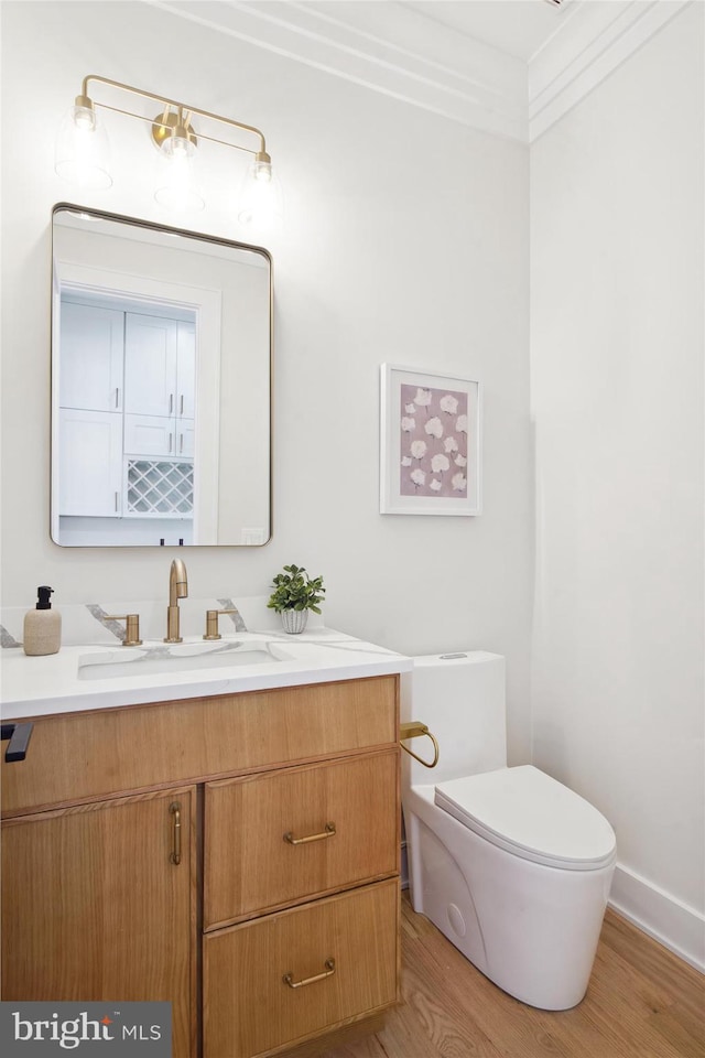 bathroom featuring ornamental molding, vanity, toilet, and hardwood / wood-style floors