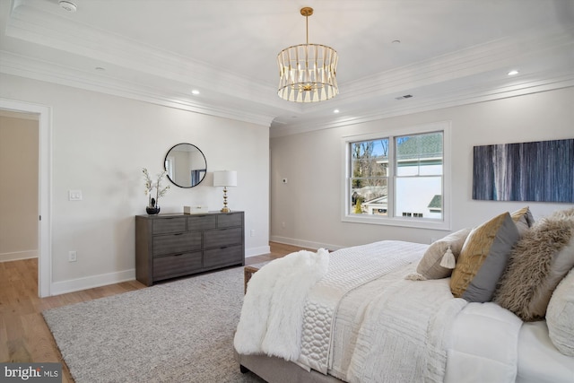 bedroom featuring an inviting chandelier, crown molding, light hardwood / wood-style floors, and a raised ceiling