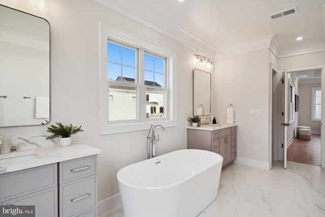 bathroom with ornamental molding, vanity, and a tub