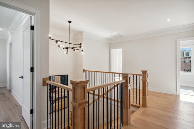 hall with an inviting chandelier, light hardwood / wood-style flooring, and ornamental molding