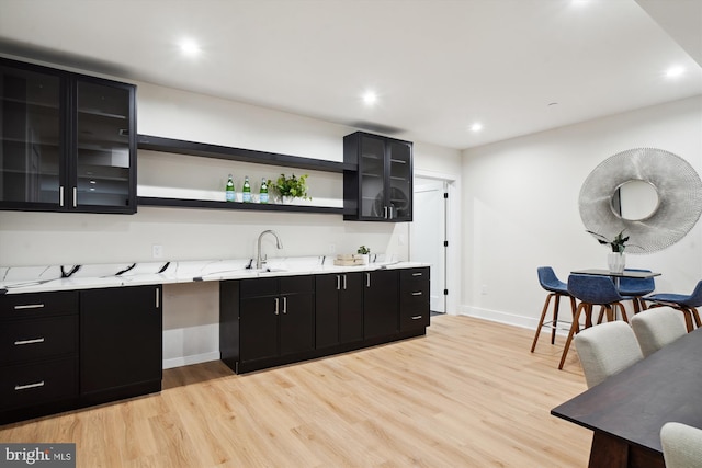 kitchen featuring sink, light stone counters, and light hardwood / wood-style flooring