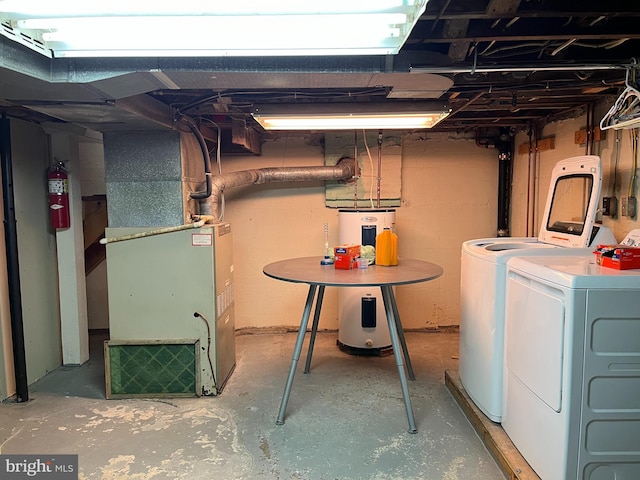 basement with washing machine and clothes dryer, electric water heater, and heating unit