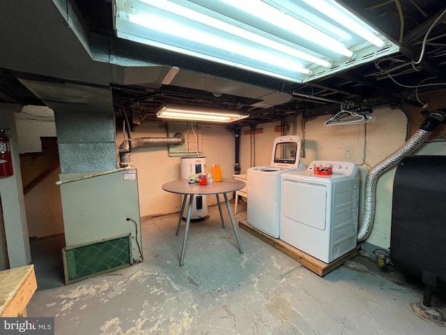 basement with electric water heater, heating unit, and separate washer and dryer