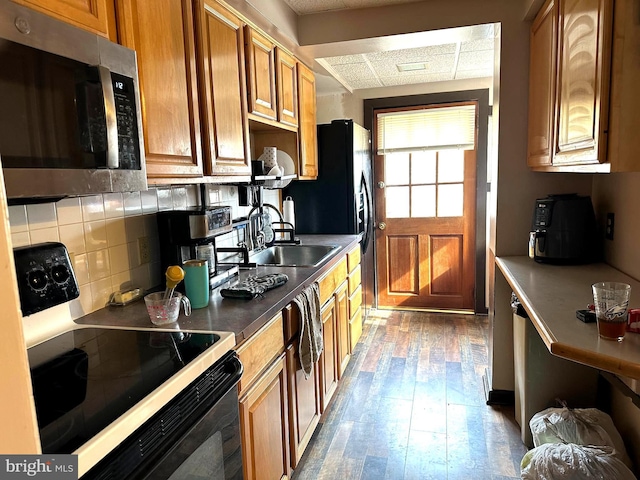 kitchen with sink, tasteful backsplash, wood-type flooring, a paneled ceiling, and black range with electric cooktop