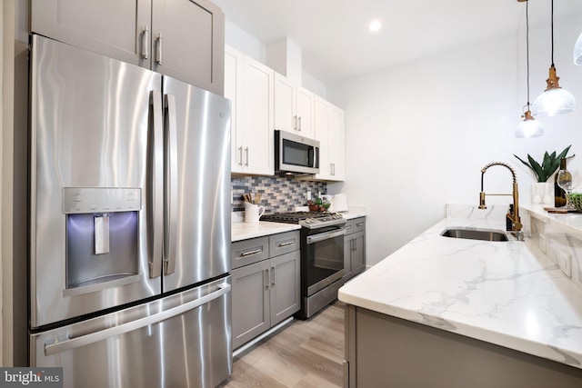 kitchen with sink, gray cabinets, appliances with stainless steel finishes, tasteful backsplash, and decorative light fixtures