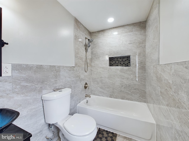 bathroom featuring tiled shower / bath, tile walls, and toilet