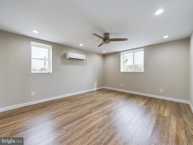 empty room featuring ceiling fan, a wall mounted AC, and light wood-type flooring